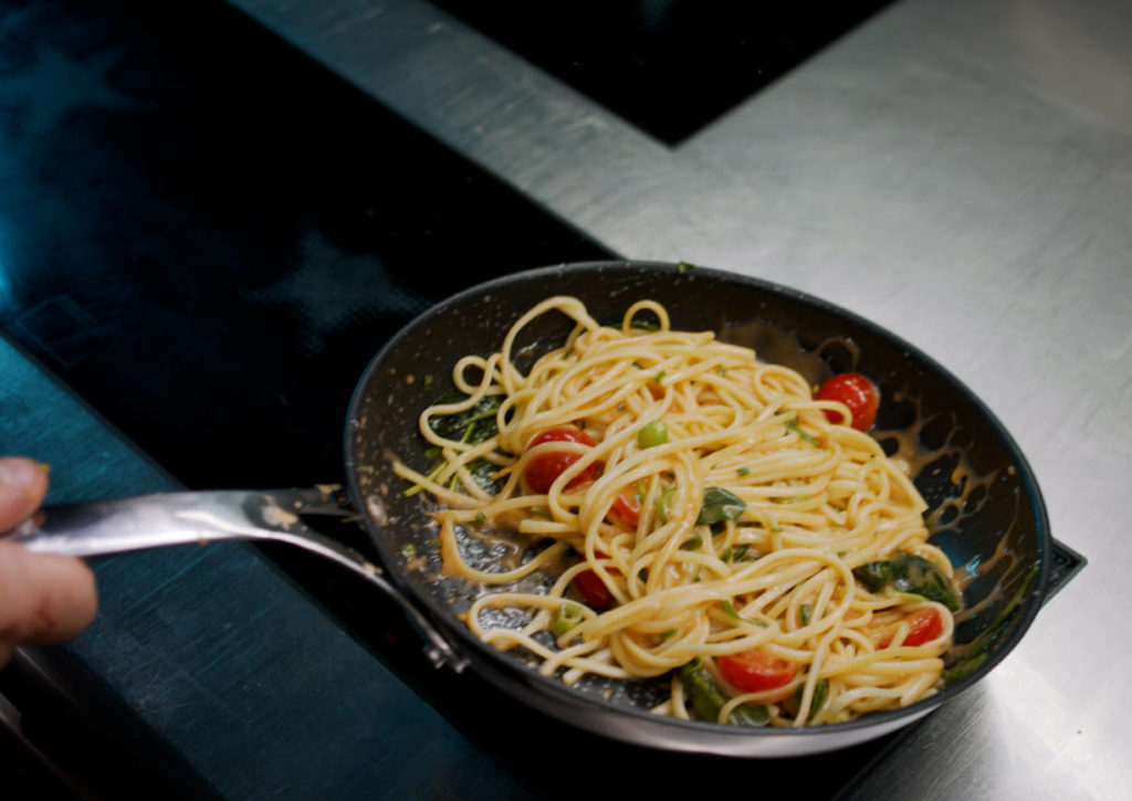 Pasta mit Kirschtomaten und Basilikum in der Pfanne geschwenkt
