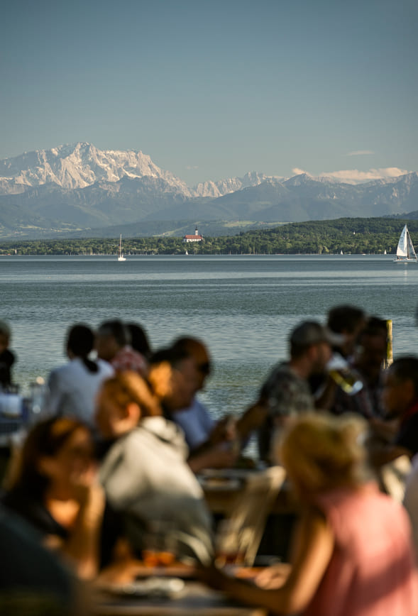 Gäste sitzen in der Strandbar mit Blick auf den Ammersee